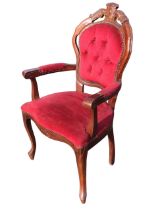 A mahogany armchair with button upholstered back with carved crest above a flared serpentine