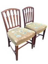 A pair of C19th mahogany Sheraton style chairs with arched backs framing leaf carved tapering