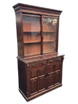 A Victorian stained bookcase cabinet with dentil cornice above a pair of sliding glass doors