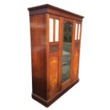 A Victorian mahogany wardrobe with moulded cornice above a central arched mirror door with foliate