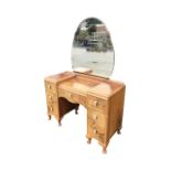 A deco walnut dressing table with cloud shaped mirror above a kneehole cabinet with shaped frieze