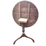 A Georgian oak tilt-top tea table with circular top on a turned column raised on a tripod base