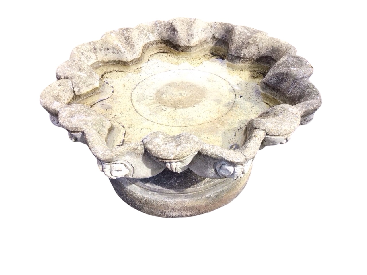 A circular composition stone garden birdbath, the scalloped bowl cast with scrolled shell medallions