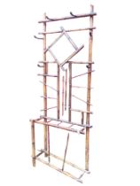 An Edwardian bamboo hallstand, the back mounted with six iron pegs and framed mirror, the base