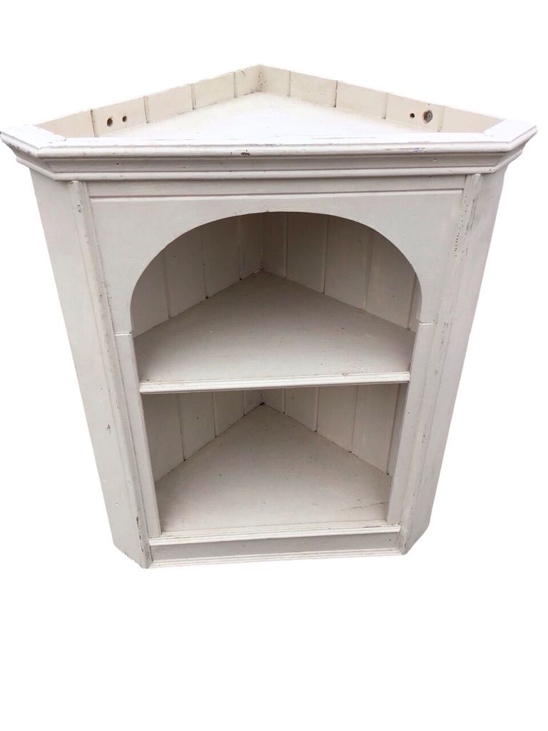 A painted pine corner cabinet with moulded cornice above an arched aperture framing two shelves