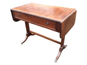 A regency style mahogany sofa table, the rectangular ribbed edge top with two drop leaves, above a
