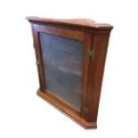 An Edwardian mahogany hanging corner cabinet with moulded cornice above a glazed door with brass