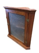 An Edwardian mahogany hanging corner cabinet with moulded cornice above a glazed door with brass
