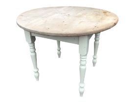 A pine kitchen table with circular top on a painted square base raised on turned tapering legs. (
