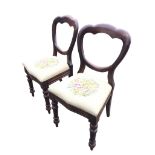 A pair of Victorian mahogany balloon-back chairs with drop-in upholstered seats, raised on turned