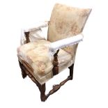 An Edwardian oak carolean style upholstered armchair, the seat with loose cushion flanked by