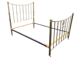 An Edwardian brass bed, the square cornerposts with cappings having applied ribbon bow decoration,