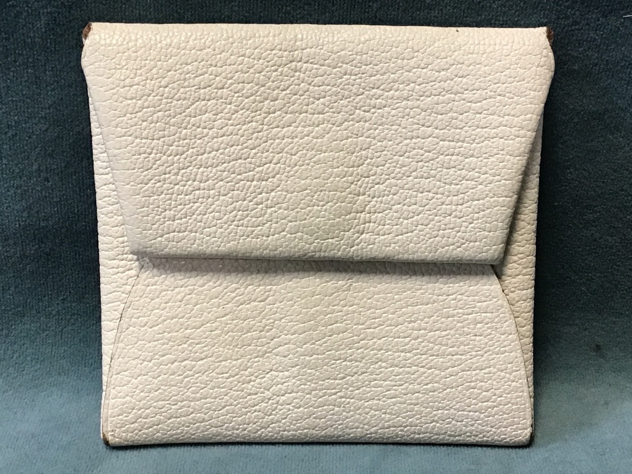 A Hermès white calfskin Bastia envelope style coin purse with snap closure.
