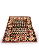 An early C20th crossstitch woolwork rug sewn with ribbon entwined bands amid floral sprigs on a