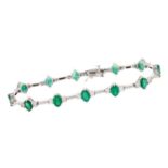 Emerald and diamond bracelet with a line of twelve oval mixed cut emeralds, each flanked by two bril