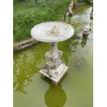 Old reconstituted stone garden fountain with circular bowl on pedestal base with lions to each corne