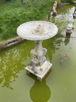 Old reconstituted stone garden fountain with circular bowl on pedestal base with lions to each corne