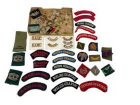 Collection of British military shoulder badges / titles, in cloth and staybrite (1 box).