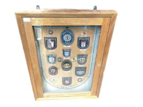 Glazed wall mounted cabinet containing a display of German Police badges.