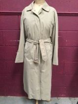 Vintage Aquascutum women's beige trench coat with check lining.