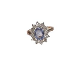 Sapphire and diamond cluster ring with an oval mixed cut cornflower blue sapphire surrounded by twel