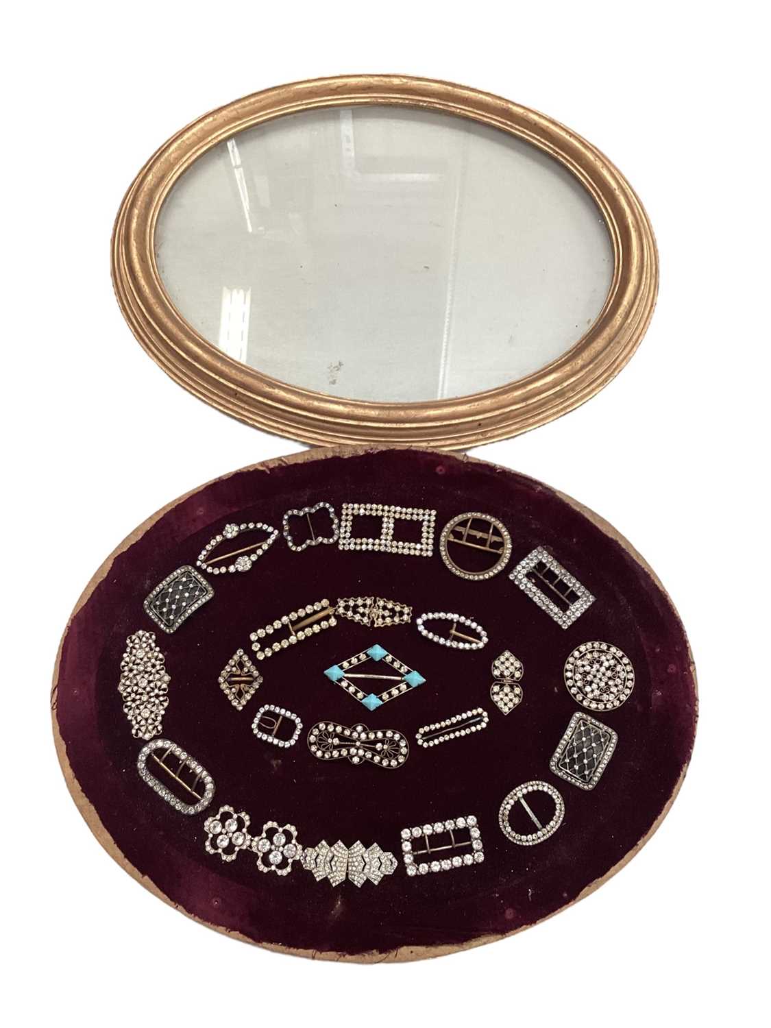 A group of paste and enamel buckles and clips mounted on velvet and in oval glazed frame. - Image 2 of 2