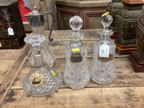 Pair of cut glass decanters with silver wine labels, and two other glass decanters