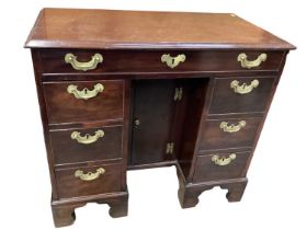 Georgian mahogany kneehole desk with seven drawers, brass handles and central cupboard below on brac