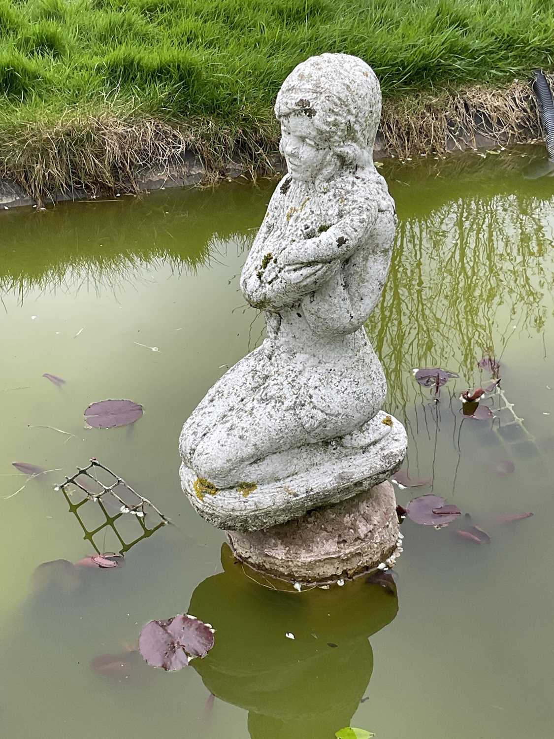 Weathered concrete garden pond fountain in the form of a kneeling lady