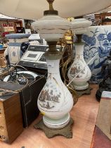 Pair of white glass table lamps with transfer printed scenes and metal mounts, together with another