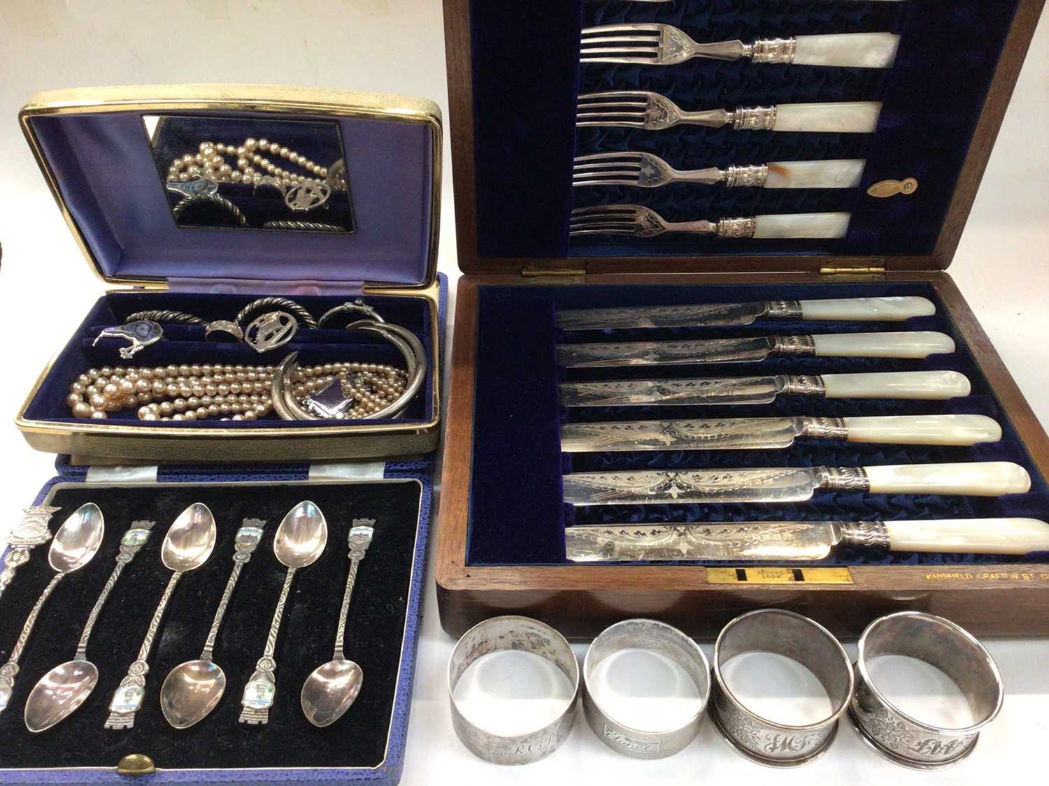 Four silver napkin rings, jewellery, plated souvenir spoons and a mother of pearl handled plated kni