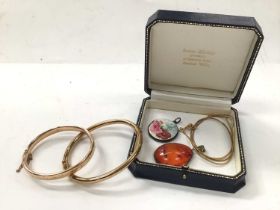 Two gold hinged bangles, silver and enamel locket and an amber pendant on plated chain