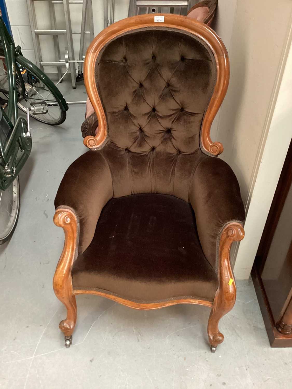Victorian spoon back armchair with buttoned brown upholstery on cabriole front legs and castors
