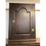 Antique oak corner cupboard with shelved interior enclosed by arched door