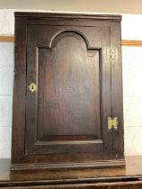 Antique oak corner cupboard with shelved interior enclosed by arched door