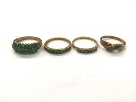 Four 9ct gold emerald/ green stone dress rings