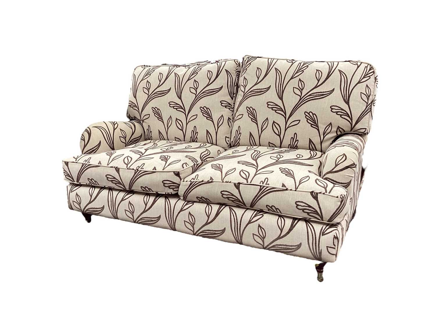 Contemporary cream two seater settee with brown leaf decoration on turned legs and brass castors, 14