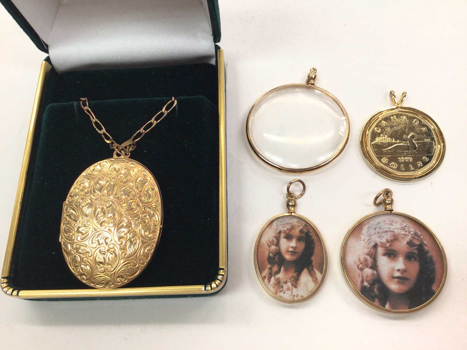 9ct gold oval locket on 9ct gold chain, three 9ct gold mounted glass lockets and a gold plated coin