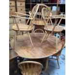 Ercol elm oval dropleaf kitchen table opening to 127 x 141cm and seven Ercol stick back chairs compr