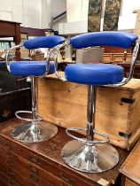Pair of contemporary stainless steel revolving bar stools with blue seats