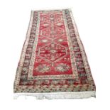Eastern rug with three central medallions on red, blue, green and brown ground, 256cm x 118cm