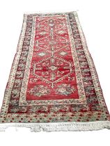 Eastern rug with three central medallions on red, blue, green and brown ground, 256cm x 118cm