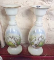 A pair of late 19th Century opaque glass vases, each with a hand painted panel, depicting a pair