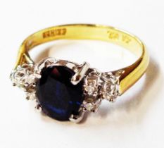 A marked 750/18k yellow metal ring, set with central oval sapphire and six flanking tiny