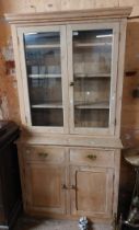 A 1.05m stripped pine dresser with shelves enclosed by a pair of glazed panel doors (one a/f) over a