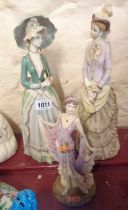 A pair of resin figurines depicting ladies in Victorian period dress holding parasols - sold with