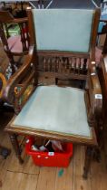 An Edwardian oak panel back elbow chair with pale green velour upholstery, set on turned front