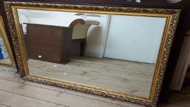 Two large gilt framed bevelled oblong wall mirrors, both with decorative floral borders