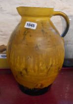 A large old terracotta milk jug, with yellow glaze finish