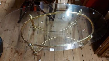 A 1.27m modern coffee table with bevelled glass oval top, set on a brass base